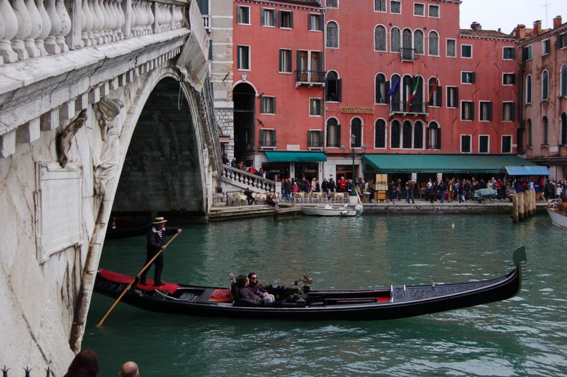Гондола проплывающая под мостом Риальто в Венеции